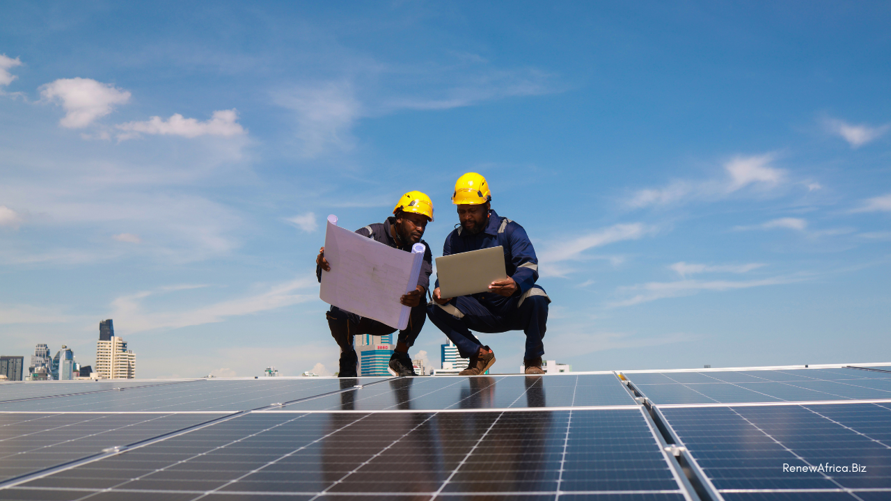 Two solar engineers reviewing a plan and laptop at a rooftop solar installation